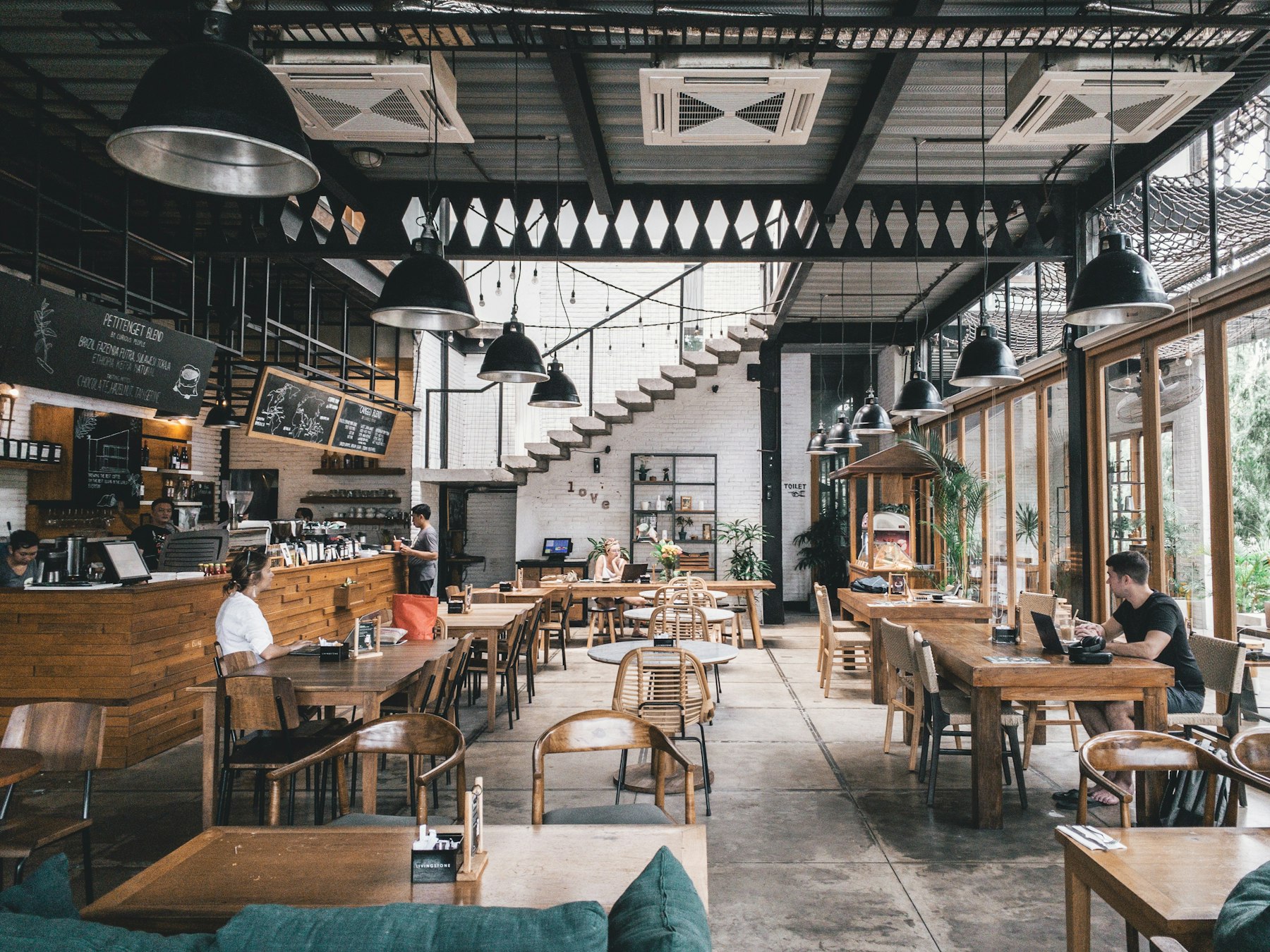 Bright cafe dining room with tables and plants.