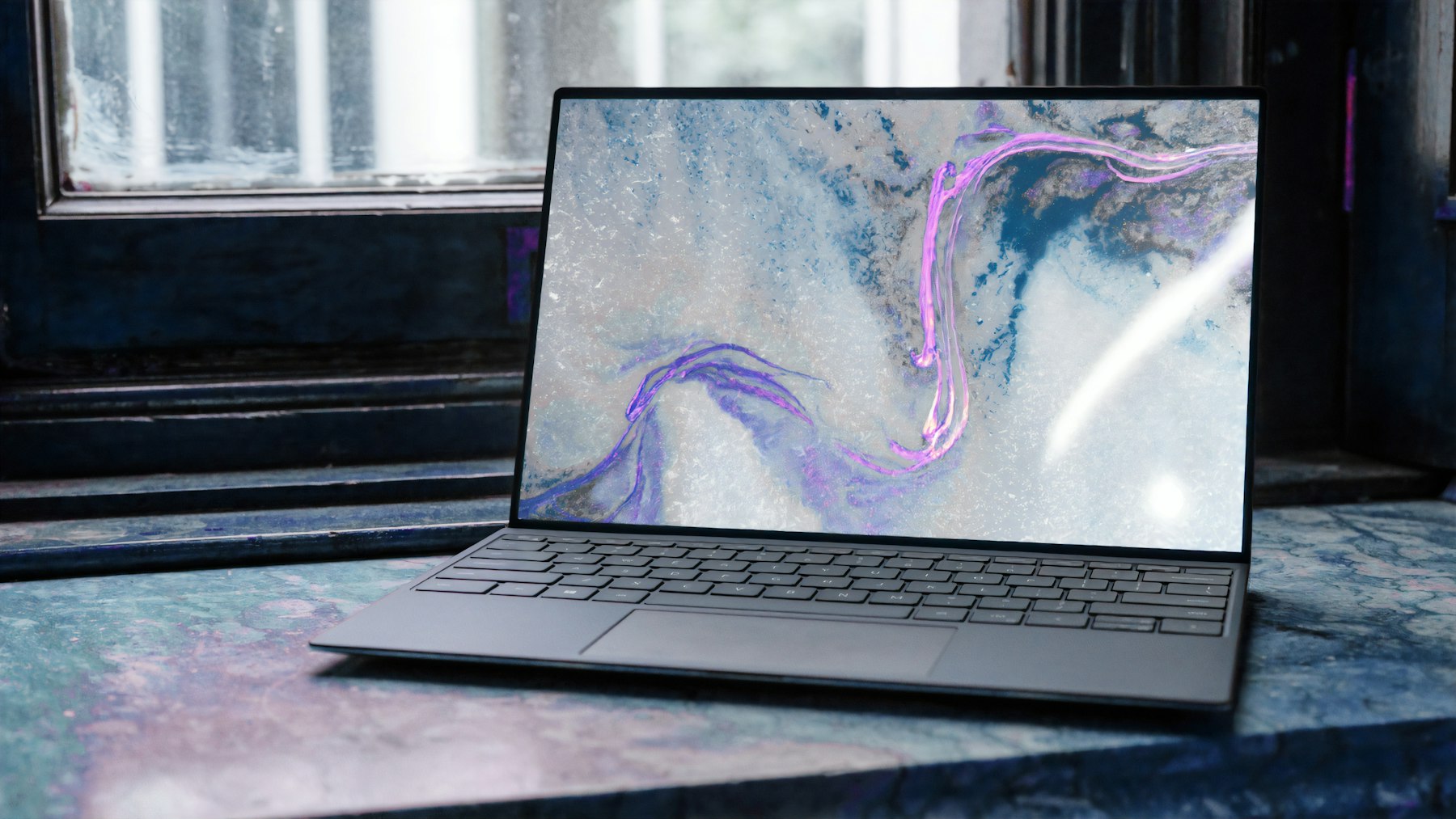 A laptop resting on a stone windowsill in soft light.